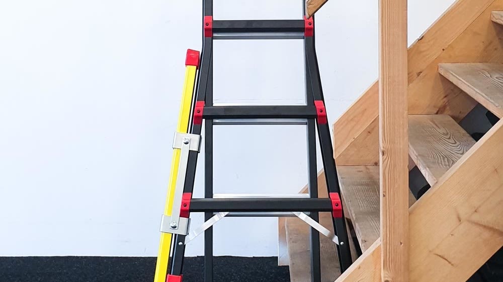 Vouwladder met gele verlengpoot naast een houten trap