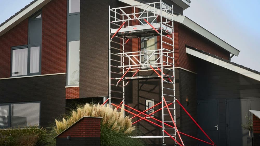 Altrex rolsteiger met leuningen op elk platform tegen de gevel van een woonhuis