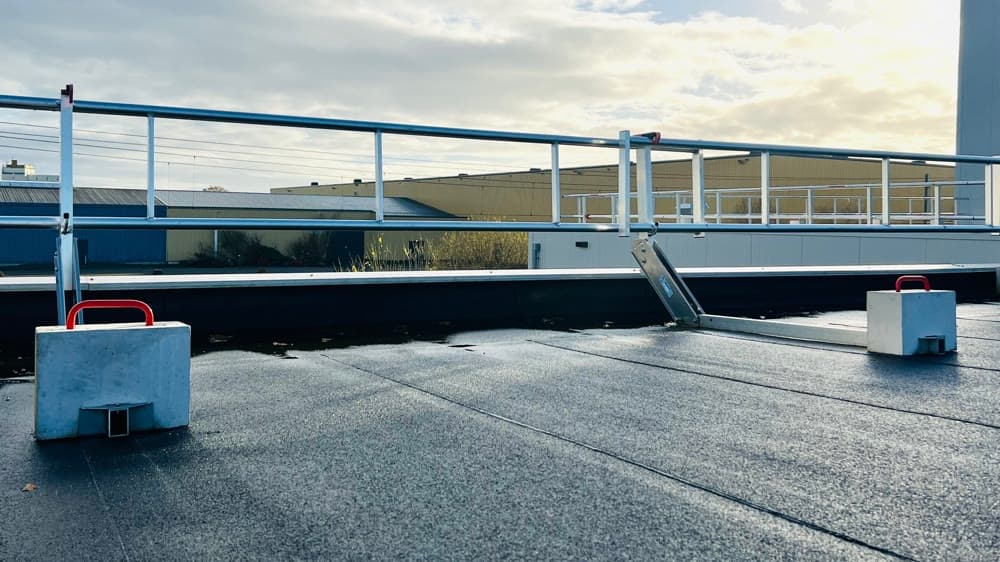 Dakrandbeveiliging met betonblokken als ballast langs de rand van een plat dak