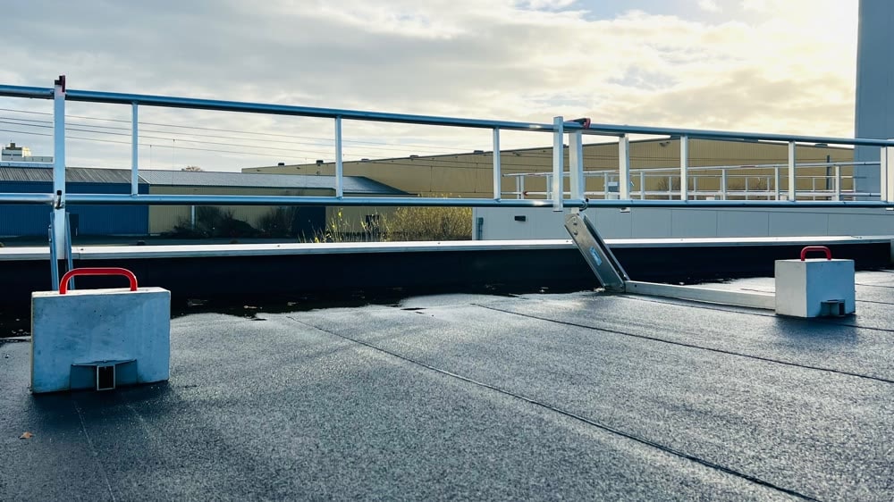 Dakrandbeveiliging met betonblokken als ballast langs de rand van een plat dak