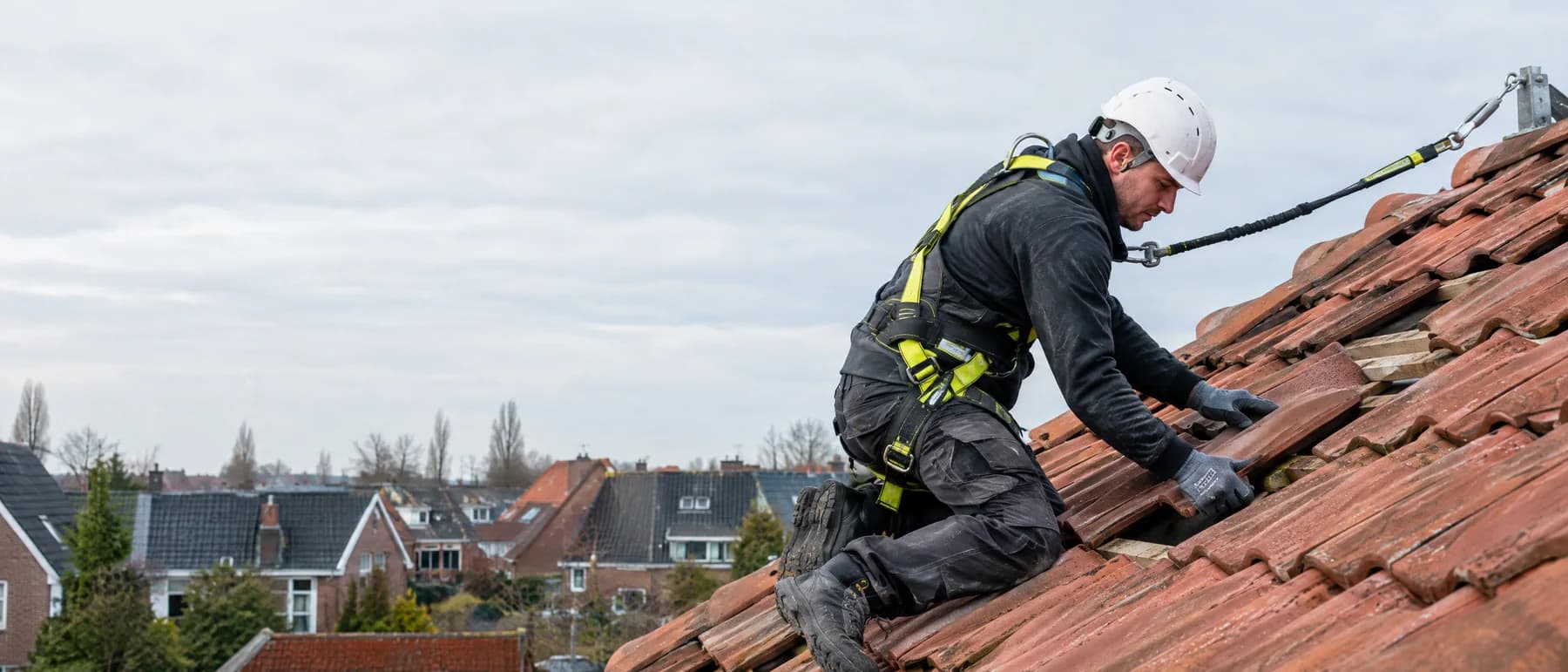 Dakdekker met valbeveiligingsharnas op een pannendak